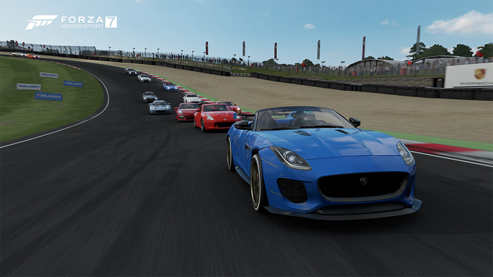 A blue sportscar leading eleven other cars in a race on a sunny day