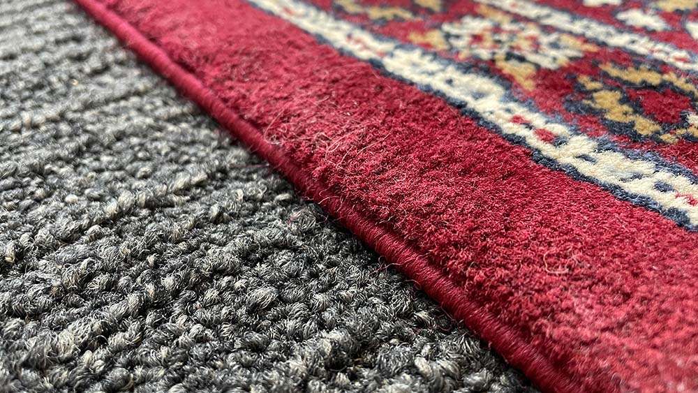 Close up of a red Persian rug on a dark carpet